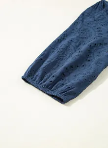Detailansicht eines blauen Oberteils mit Lochstickerei und elastischem Ärmelbündchen.