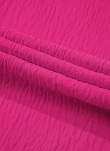 Close-up macro shot of vibrant pink wrinkled fabric texture for summer jumpsuit