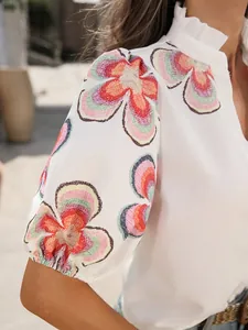 Gros plan d'un haut blanc à imprimé floral coloré avec des manches bouffantes élégantes