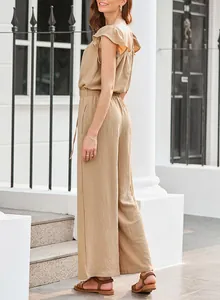 Side view of a beige ruffle-sleeved pleated jumpsuit with pockets and wide legs.