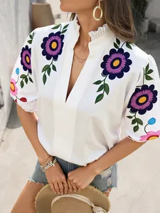Détail du haut blanc à col en V pour femme avec broderie florale violette et col montant