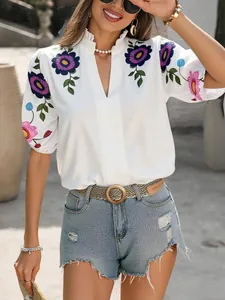 Détail d'un haut blanc élégant avec col en V et broderies florales sur les manches