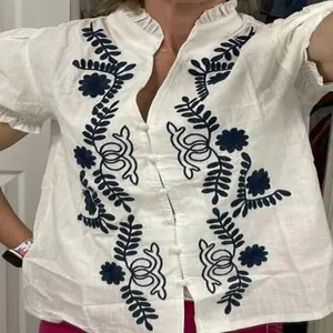 Vue détaillée d'une blouse en coton blanc avec broderies bleues et manches bouffantes