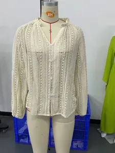 Gros plan sur la dentelle florale complexe et les boutons de cette chemise écrue