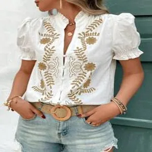 Détail d'une blouse en coton blanc avec broderie et manches bouffantes élégantes