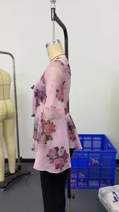Dettaglio di una blusa in chiffon a fiori con scollo quadrato e maniche a campana.