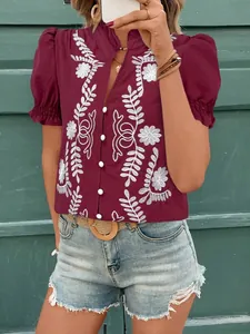 Détail de la blouse en coton bordeaux avec broderie florale et manches bouffantes.