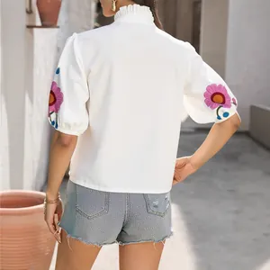 Haut d'été blanc élégant avec col montant, manches bouffantes et broderie florale