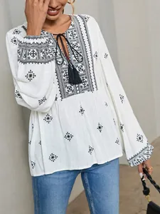 Detailed view of white ethnic embroidered blouse with tassel neck and lantern sleeves