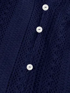 Gros plan sur la dentelle ajourée bleu marine et les boutons blancs d'une chemise