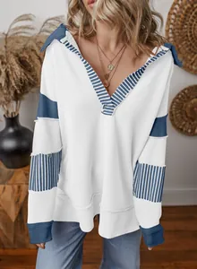 Close-up view of loose V-neck sweatshirt featuring blue striped patchwork details