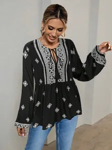 Close-up of women's vintage ethnic style black blouse with tassel tie and lantern sleeves.