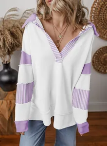 Close-up view of white deep V-neck sweatshirt with purple striped patchwork details.