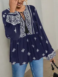 Detail of retro ethnic navy blouse with tassels and white geometric embroidery.