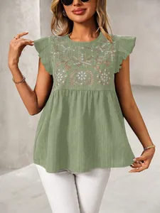 Gedetailleerde weergave van borduurwerk en ruffelmouwen op deze groene blouse