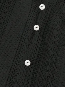 Détail du tissu en dentelle noire ajourée avec d'élégants boutons blancs brillants