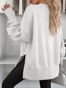 Détail d'un sweat-shirt blanc surdimensionné à col rond avec fentes latérales.