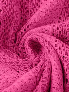 Gros plan sur la texture de dentelle rose vif ajourée avec motif tricoté floral