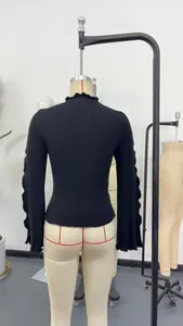 Vista posteriore del top nero a lupetto con eleganti maniche a campana con volant.