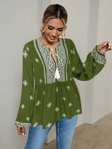 Close-up detail of a vintage ethnic green blouse with tie-up collar and white embroidery