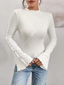 Dettaglio top bianco a coste con collo alto, cuciture asimmetriche e maniche a campana