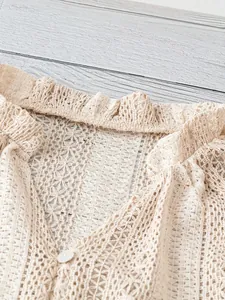 Gros plan d'un chemisier en dentelle beige avec décolleté en V, col volanté et bouton.
