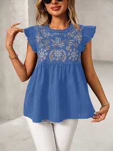 Detailopname van etnisch borduurwerk op blauwe blouse met korte mouwen en ruches.