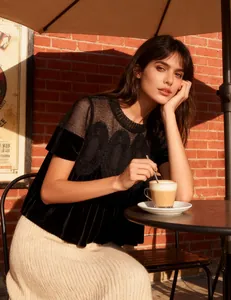 Close-up detail of mesh lace embroidery on a elegant black velvet loose-fit top worn by a model