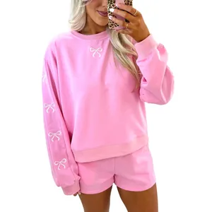 Completo casual rosa a due pezzi con fiocchi ricamati su felpa e pantaloncini.