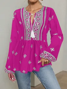 Detailed view of magenta ethnic blouse featuring white embroidery and tassel tie neck