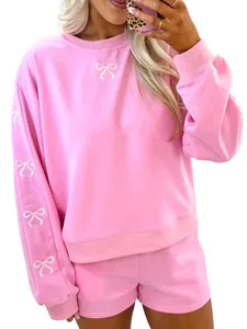 Dettaglio del set felpa e pantaloncini rosa con ricamo a fiocco bianco sulle maniche
