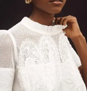 Détail de la dentelle blanche complexe et de la broderie en résille du haut