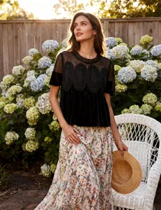 Elegant black velvet top with mesh embroidery and delicate lace detailing in a garden setting