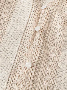 Gros plan sur la texture complexe de la dentelle ajourée et des boutons blancs sur chemise beige