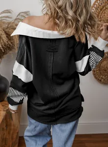 Back view detail of a loose black sweatshirt with white panels and striped cuffs