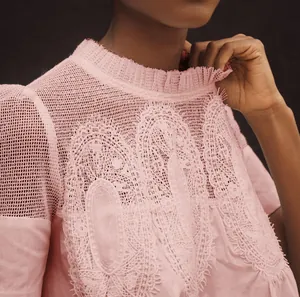 Détails de broderie en dentelle rose et mesh sur un chemisier élégant à col rond