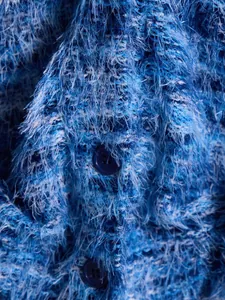 Close-up macro detail of blue fuzzy shaggy knit cardigan fabric and dark buttons