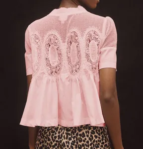 Gros plan sur la broderie en dentelle au dos d'une blouse rose à manches courtes.
