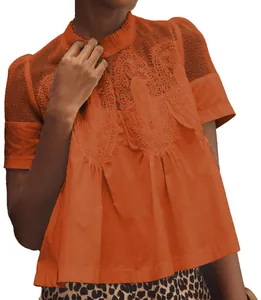 Gros plan d'un haut orange à manches courtes avec broderie de dentelle et détails en mesh