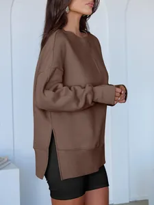 Détail d'un sweat-shirt marron surdimensionné avec fentes latérales et épaules tombantes.