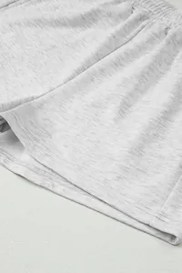 Dettaglio di pantaloncini in cotone grigio melange con trama del tessuto e cuciture fini.