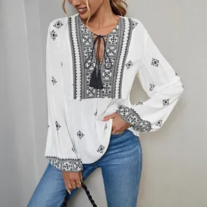 Vintage boho white embroidered blouse featuring tassel tie-neck and loose lantern sleeves