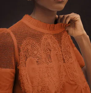Vue détaillée du haut orange terre cuite avec broderie en dentelle et col montant volanté