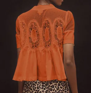 Détail du dos d'un haut orange à manches courtes avec broderie élégante et basque.