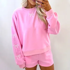 Set coordinato felpa rosa oversize e pantaloncini con elegante ricamo a fiocco bianco.
