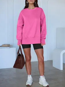 Sweat-shirt oversize rose vif à col rond associé à un short de cycliste noir pour le sport.
