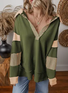 Detailed view of loose green V-neck sweatshirt featuring striped patchwork designs.