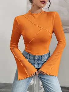 Dettaglio di maglia arancione a coste con maniche a campana e cuciture asimmetriche