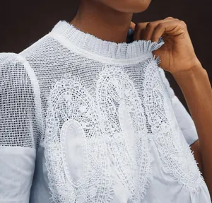 Gros plan de la broderie en dentelle florale blanche et épaule en résille, haut bleu