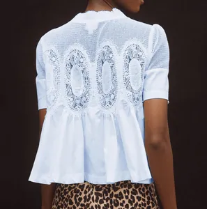 Détail du dos d'une blouse bleue à manches courtes avec broderie dentelle et tulle.